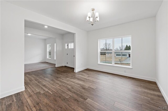 unfurnished room featuring baseboards, dark wood-type flooring, visible vents, and a notable chandelier