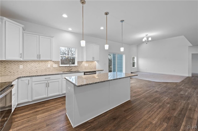 kitchen with dark wood-style flooring, a sink, white cabinets, appliances with stainless steel finishes, and tasteful backsplash