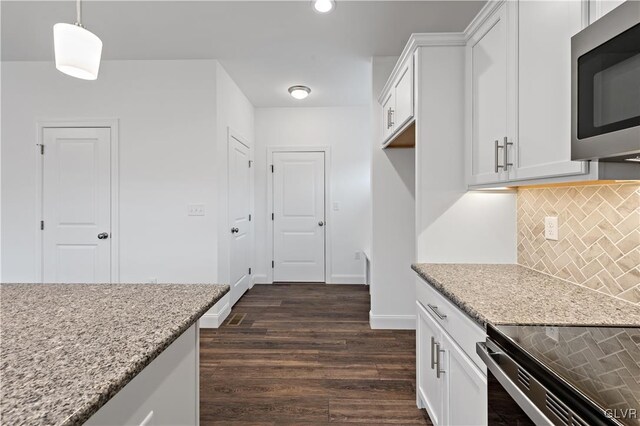 kitchen with dark wood-style floors, white cabinetry, stainless steel microwave, and light stone counters