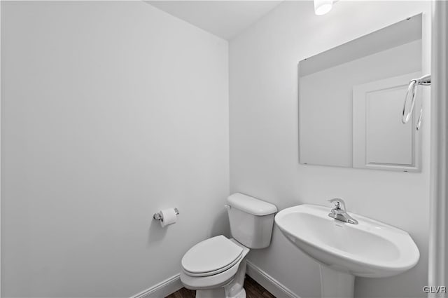 bathroom featuring wood finished floors, a sink, toilet, and baseboards