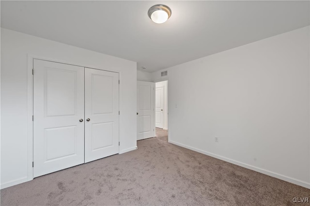 unfurnished bedroom featuring carpet, visible vents, baseboards, and a closet