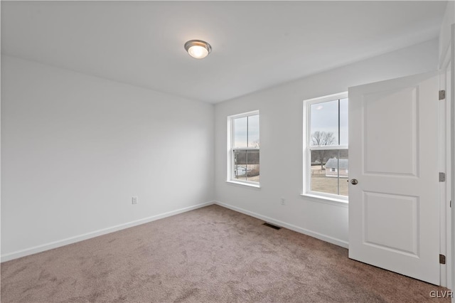 carpeted empty room featuring visible vents and baseboards