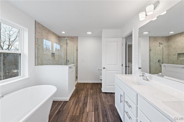 full bathroom with wood finished floors, a shower stall, vanity, and baseboards