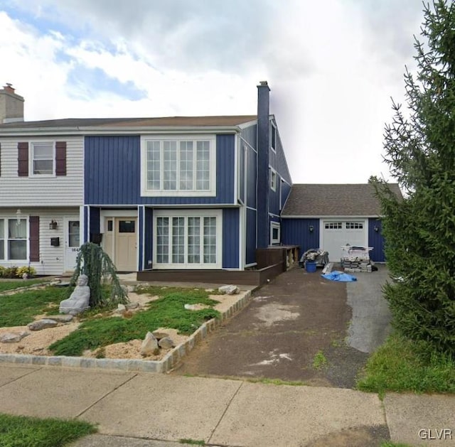 view of front of property with aphalt driveway, a chimney, and a garage