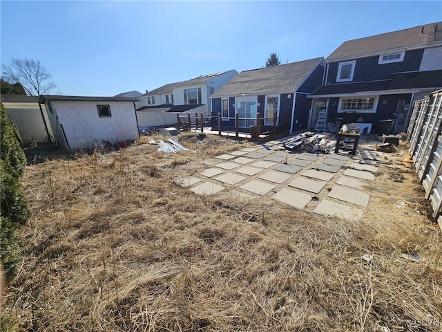 back of house featuring an outdoor fire pit, a patio area, fence, and an outbuilding