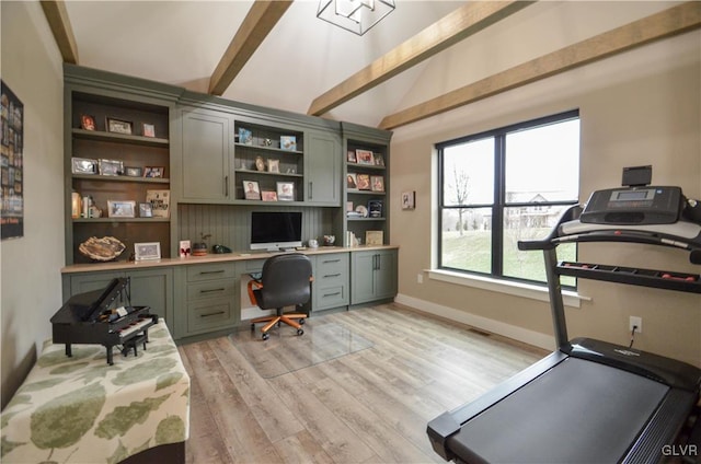 home office featuring lofted ceiling with beams, built in desk, light wood-type flooring, and baseboards