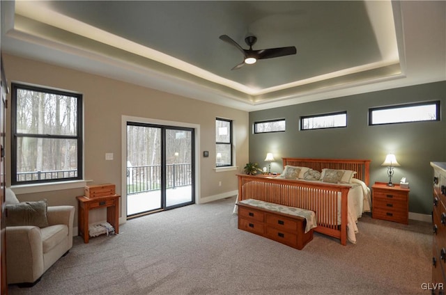 bedroom featuring access to exterior, a tray ceiling, carpet floors, and baseboards