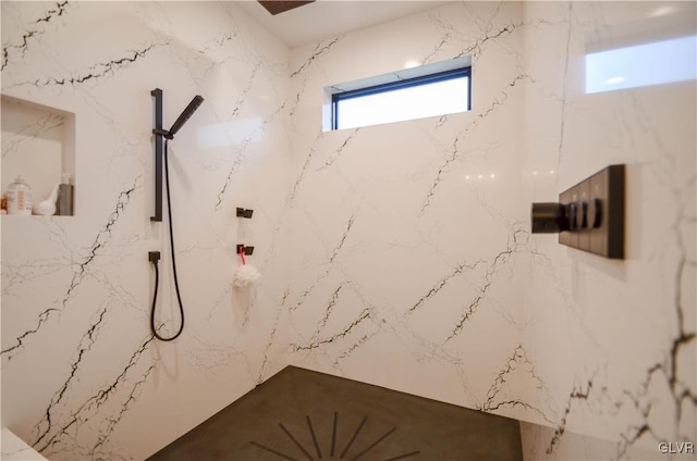 bathroom featuring a marble finish shower and stone wall