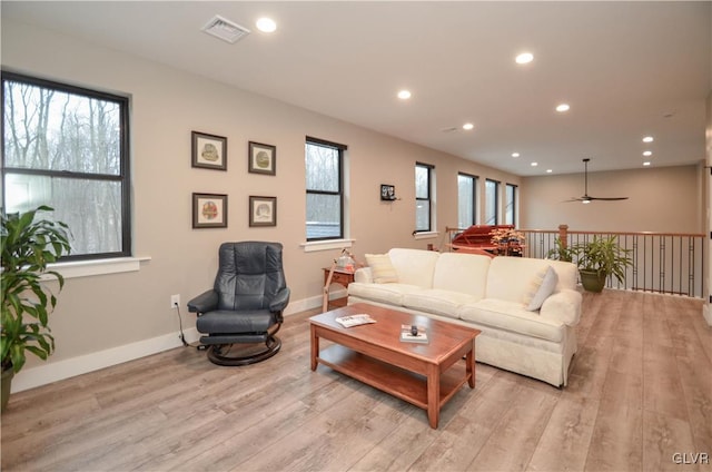 living room featuring baseboards, light wood-type flooring, visible vents, and recessed lighting