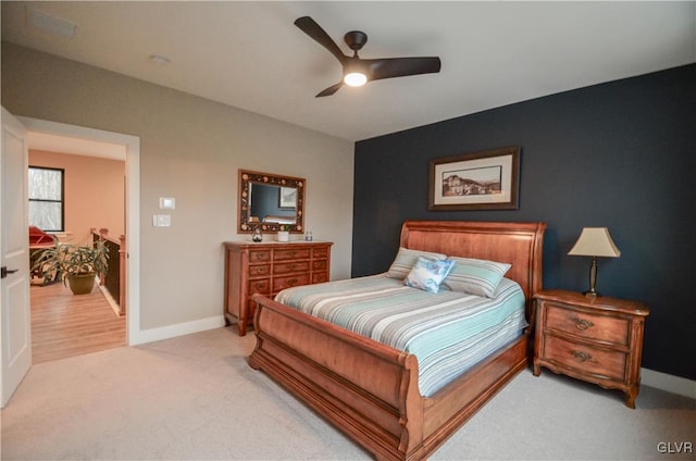 bedroom featuring light carpet, a ceiling fan, and baseboards