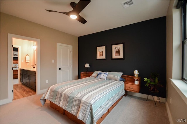 bedroom featuring baseboards, visible vents, connected bathroom, and light colored carpet