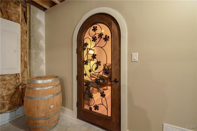 wine room with arched walkways, visible vents, and electric panel