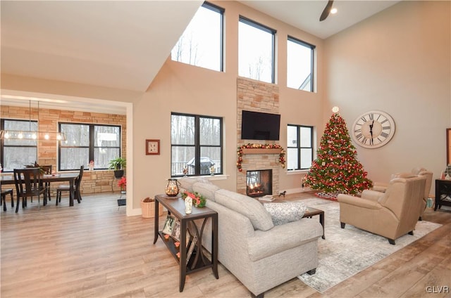 living room with a towering ceiling, baseboards, wood finished floors, and a glass covered fireplace