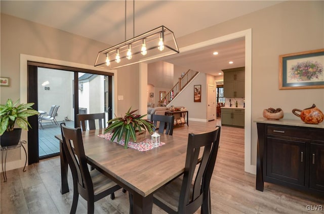 dining area featuring light wood-type flooring, baseboards, stairway, and recessed lighting