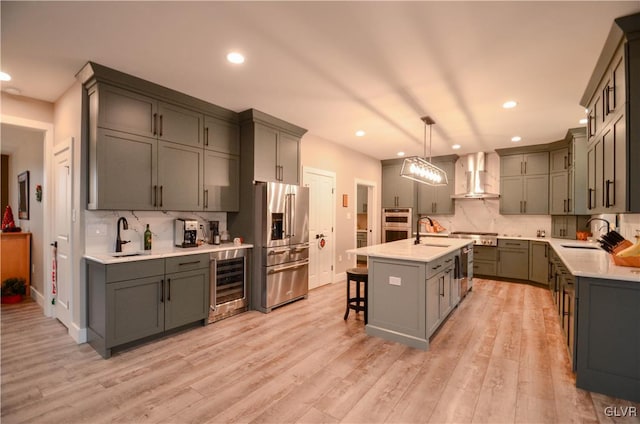 kitchen with stainless steel appliances, wine cooler, a sink, and wall chimney exhaust hood