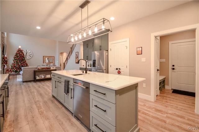 kitchen with appliances with stainless steel finishes, light wood-style floors, a sink, and gray cabinetry