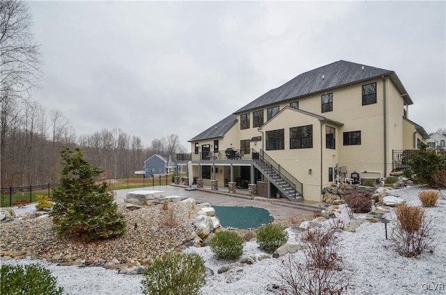 rear view of house with stucco siding, fence, a patio, and stairs