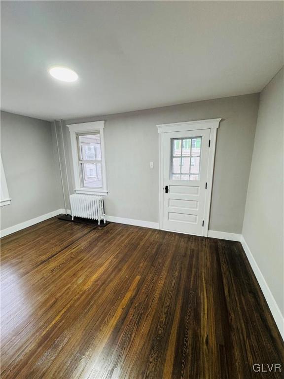 entrance foyer featuring baseboards, radiator heating unit, and wood finished floors