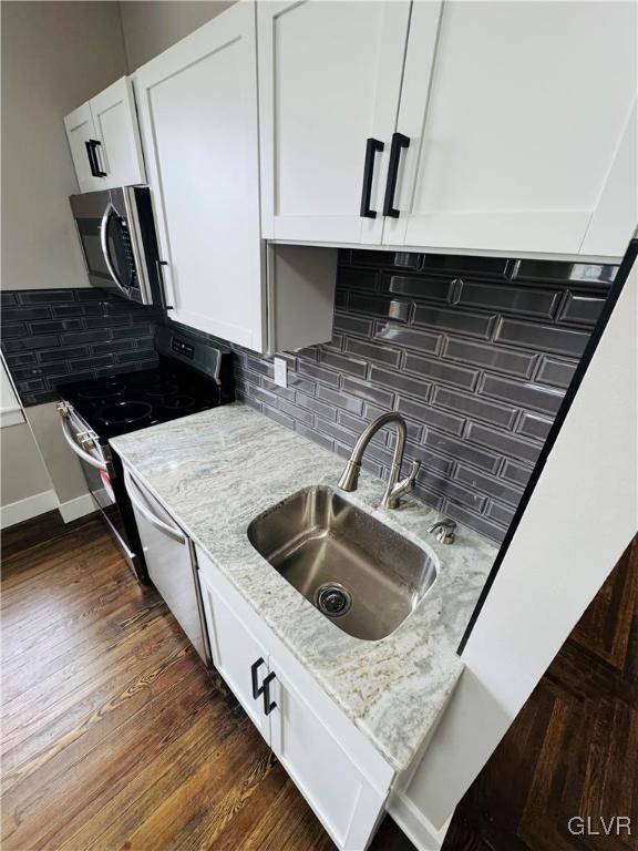 kitchen featuring electric stove, stainless steel microwave, dark wood-type flooring, white cabinets, and a sink