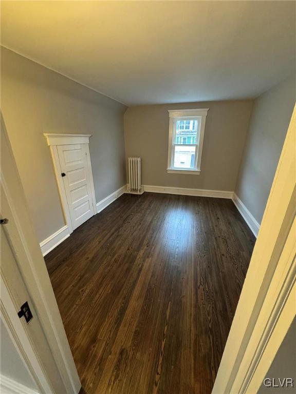 bonus room featuring lofted ceiling, radiator, dark wood finished floors, and baseboards