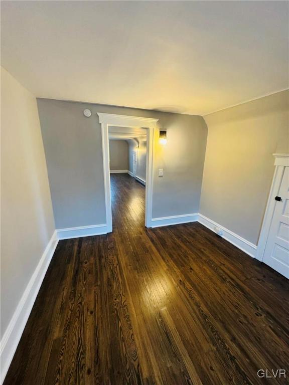 unfurnished room with dark wood-style flooring and baseboards