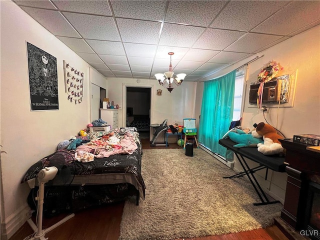 bedroom with a chandelier, a drop ceiling, and a wall unit AC