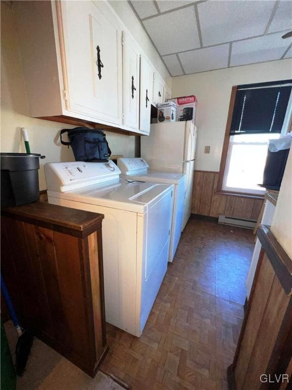 laundry area featuring a baseboard radiator, cabinet space, wainscoting, wooden walls, and independent washer and dryer