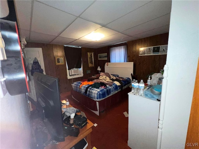 bedroom featuring wood walls and a paneled ceiling