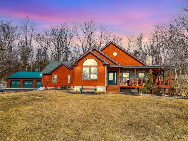 view of front of home with covered porch, a front lawn, a chimney, and an outdoor structure