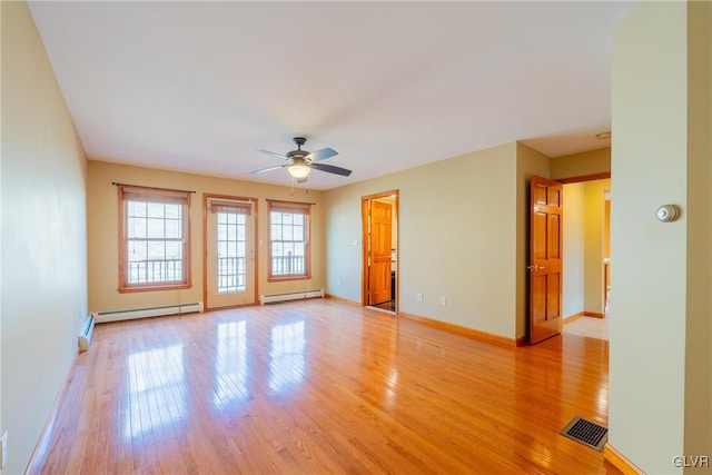 spare room with baseboards, visible vents, a ceiling fan, baseboard heating, and light wood-type flooring