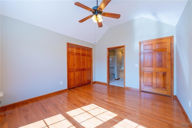 unfurnished bedroom featuring baseboards, lofted ceiling, ensuite bathroom, light wood-type flooring, and a closet