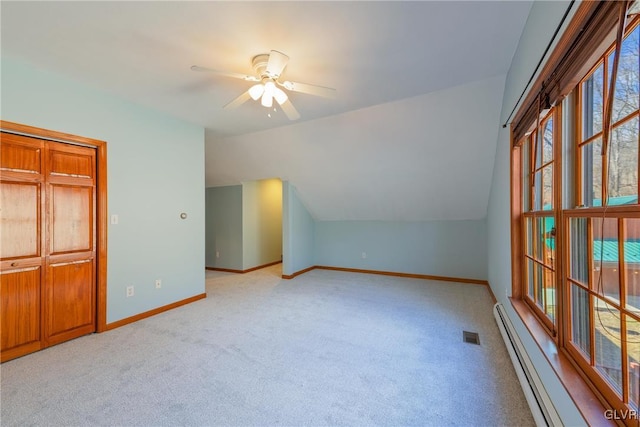 additional living space featuring lofted ceiling, light carpet, a ceiling fan, baseboards, and baseboard heating