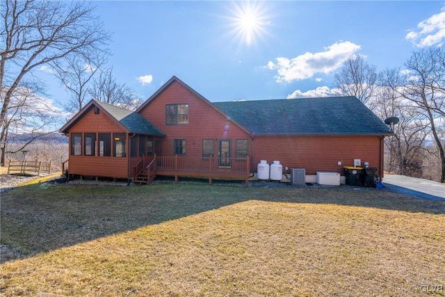 rear view of property featuring a yard, a shingled roof, central AC unit, a sunroom, and a deck