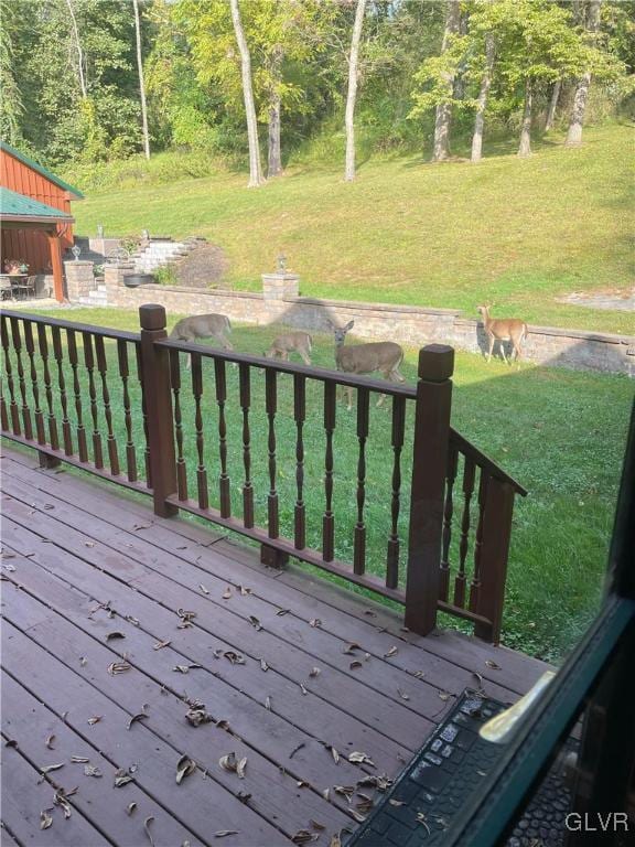 wooden deck with a forest view and a lawn