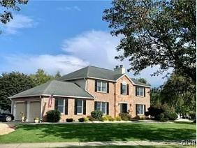 view of front of property with a garage, driveway, a chimney, and a front lawn