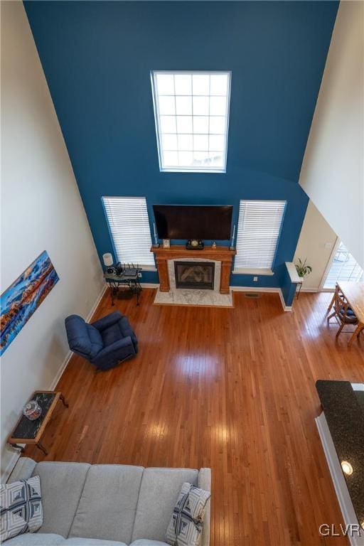 living room featuring a fireplace with flush hearth, baseboards, and wood finished floors