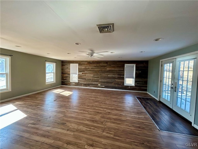 spare room with wooden walls, baseboards, wood finished floors, french doors, and recessed lighting