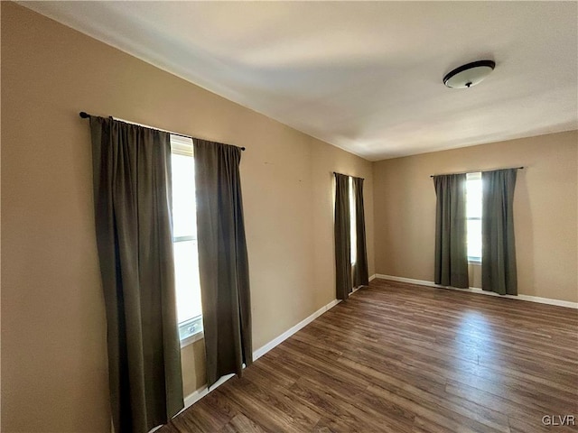 empty room with dark wood-type flooring and baseboards