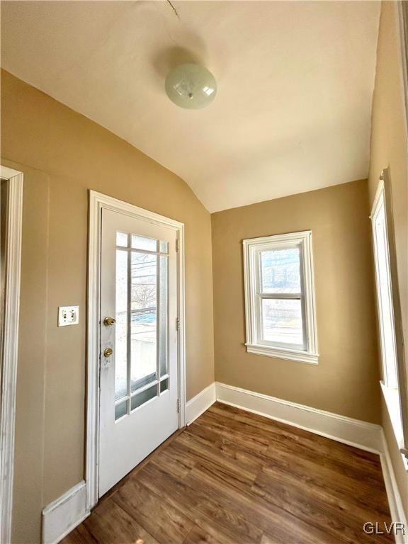 doorway featuring baseboards, vaulted ceiling, and dark wood-type flooring