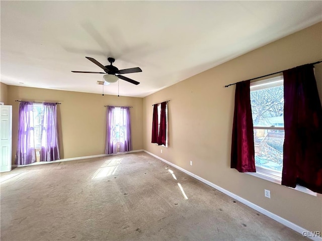 carpeted spare room featuring ceiling fan and baseboards