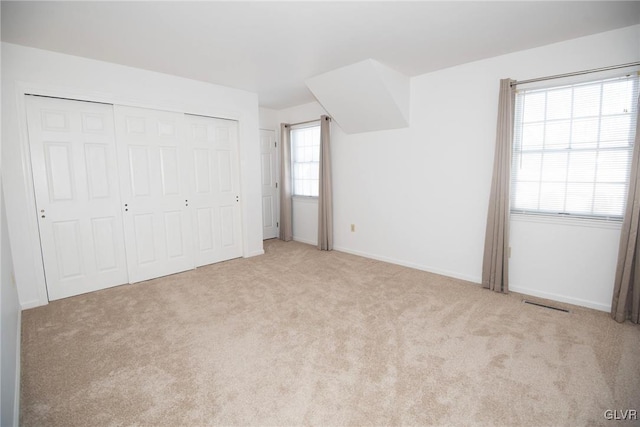 unfurnished bedroom with a closet, carpet, visible vents, and baseboards