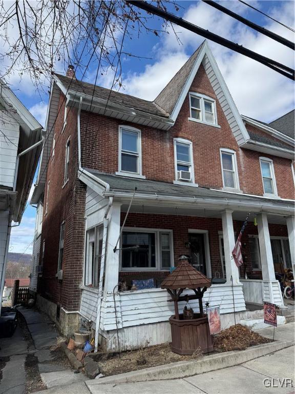 multi unit property featuring a chimney, a porch, cooling unit, and brick siding