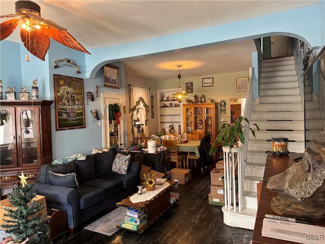 living area featuring a ceiling fan, stairs, arched walkways, and wood finished floors