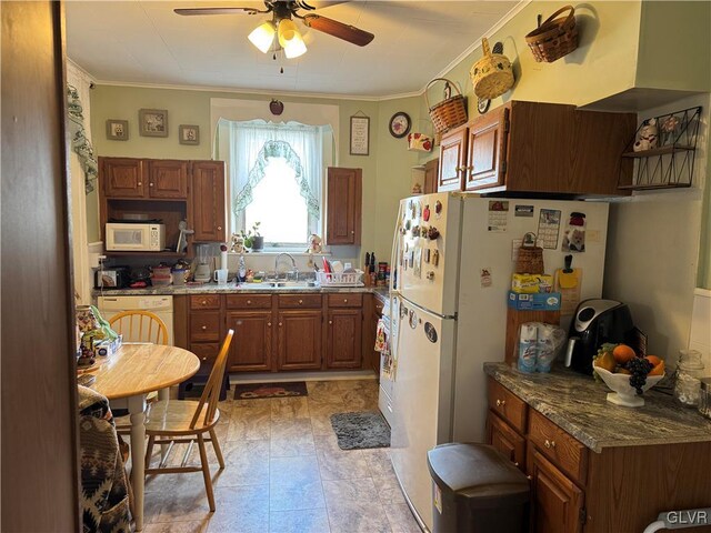kitchen featuring white appliances, ornamental molding, brown cabinetry, and a sink