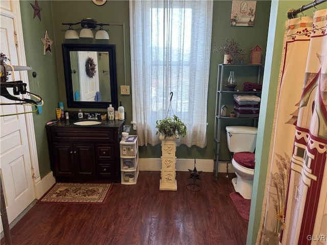 bathroom with baseboards, vanity, toilet, and wood finished floors