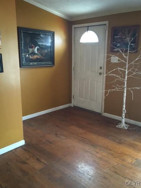 foyer entrance with ornamental molding, hardwood / wood-style flooring, and baseboards