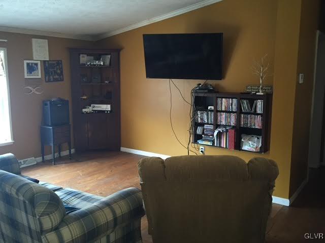 living area with baseboards, ornamental molding, and wood finished floors