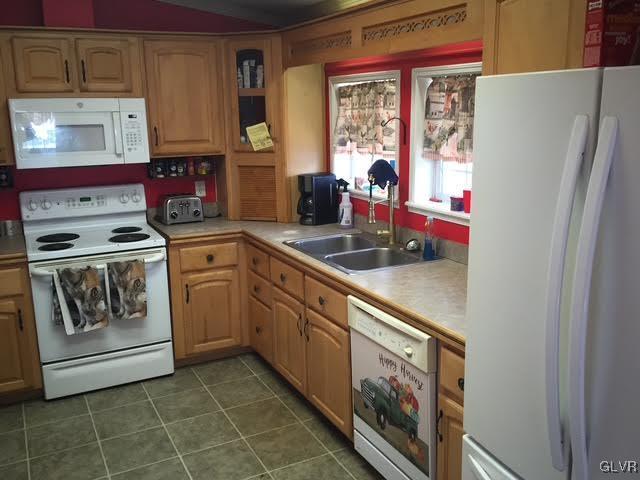 kitchen with a toaster, white appliances, dark tile patterned flooring, a sink, and light countertops