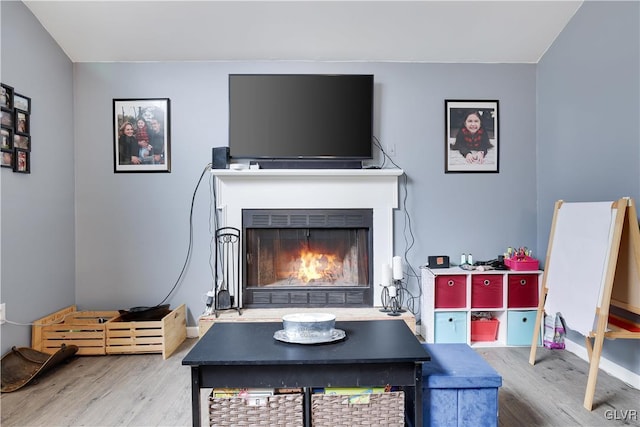 interior space with a lit fireplace and wood finished floors