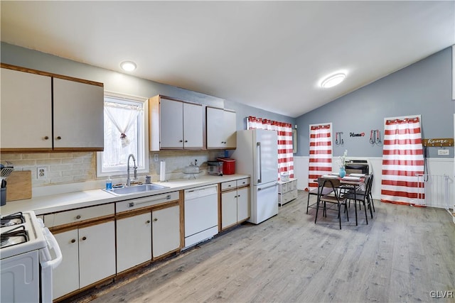 kitchen with light wood-style flooring, white appliances, a sink, vaulted ceiling, and light countertops